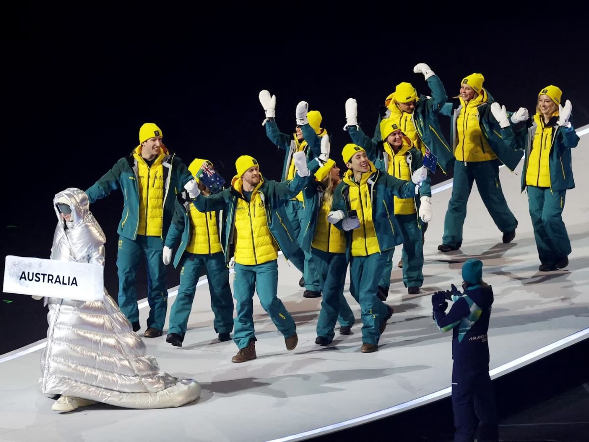 Team Australia parades during the Milano Cortina 2026 Winter Olympics opening ceremony, with athletes in green-and-gold uniforms waving Australian flags to the crowd.