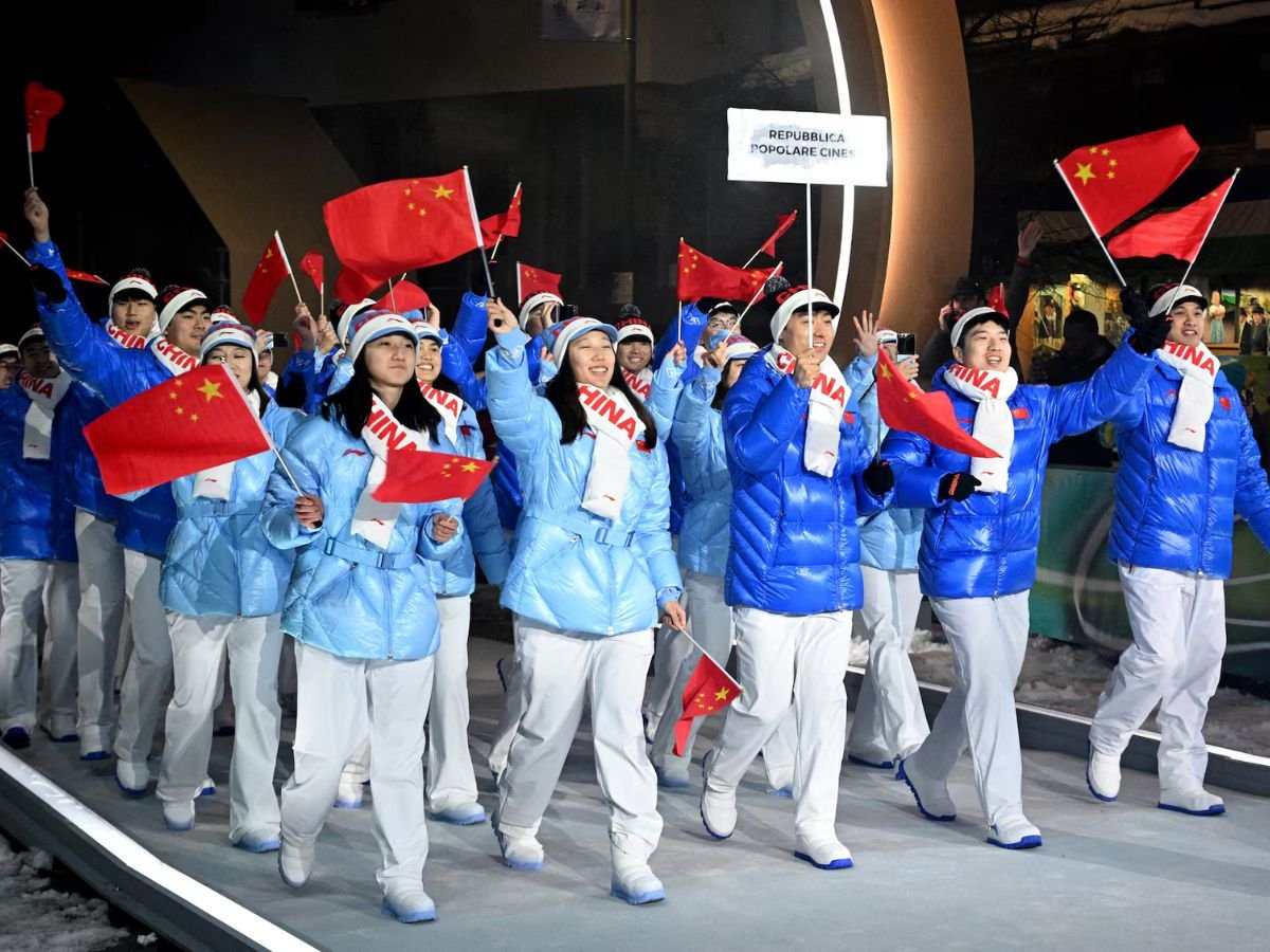 Team China parades at the Milano Cortina 2026 Winter Olympics opening ceremony, with athletes waving Chinese flags as they enter the stadium.