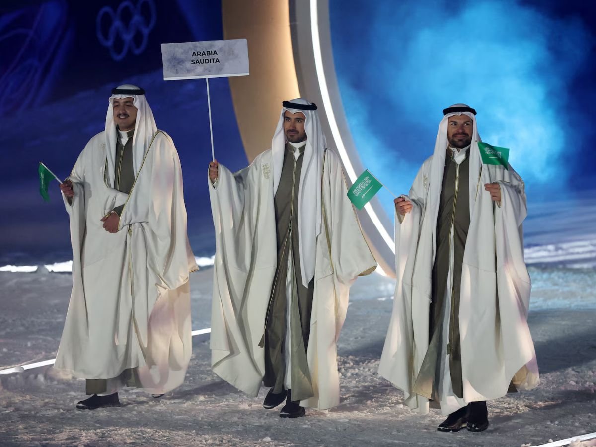 Team Saudi Arabia parades at the Milano Cortina 2026 Winter Olympics opening ceremony, with athletes wearing traditional Saudi attire and carrying the national flag.