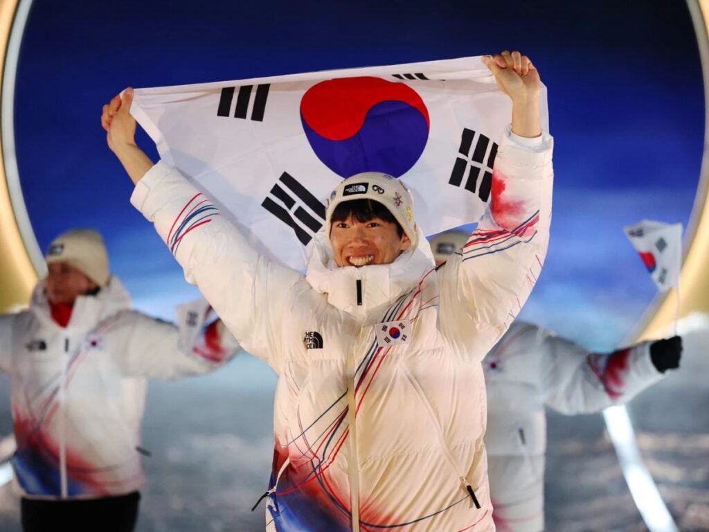 A South Korean athlete holds the national flag high as Team South Korea parades during the Milano Cortina 2026 Winter Olympics opening ceremony in Livigno.