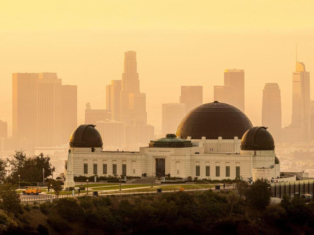 Griffith Observatory overlooking the hazy Downtown Los Angeles skyline in golden light