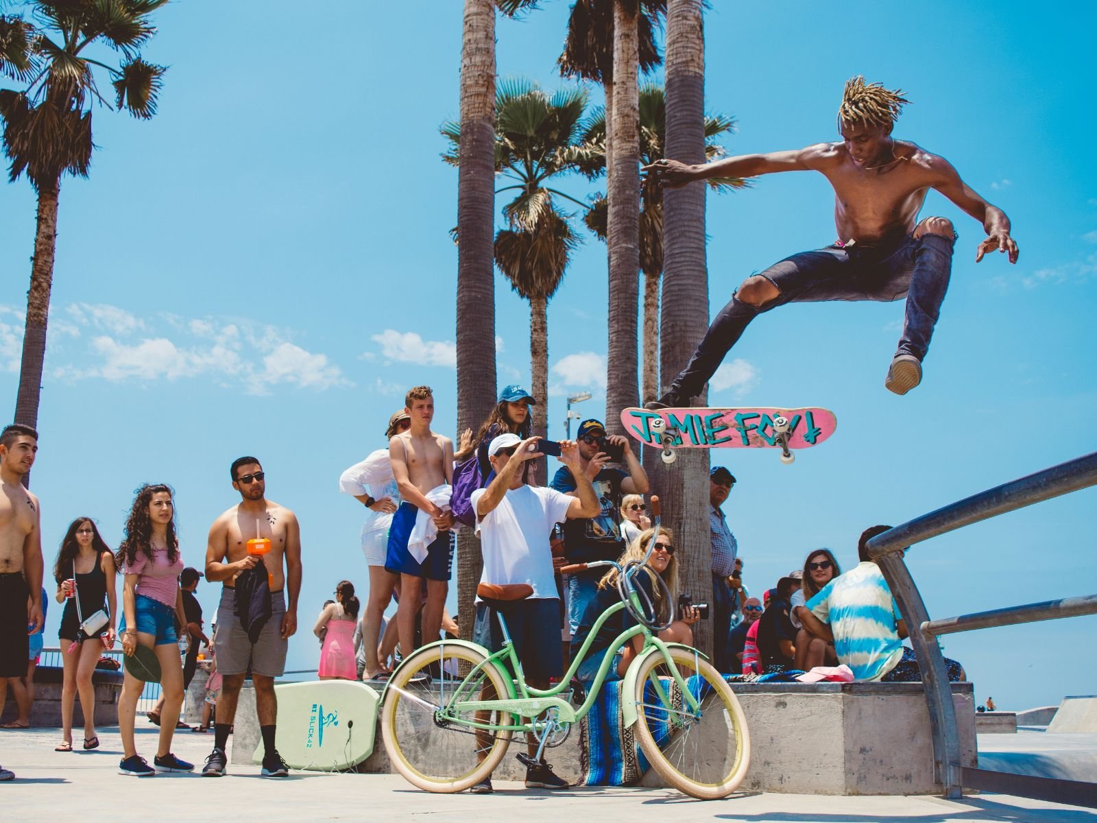 Skateboarder performing an aerial trick in front of spectators at Venice Beach Skatepark.