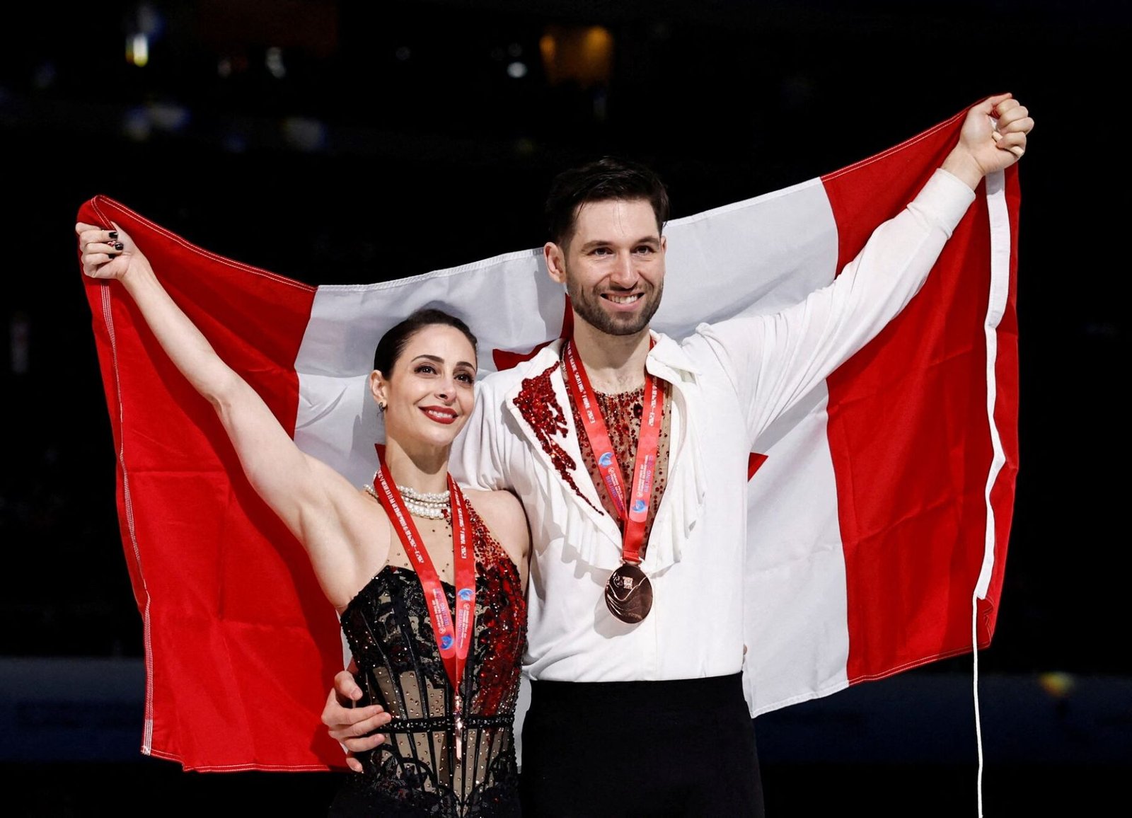 Deanna Stellato-Dudek and Maxime Deschamps of Canada celebrate with the Canadian flag after winning bronze in the pairs event at the ISU Grand Prix of Figure Skating Final in Beijing, China, on December 8, 2023.
